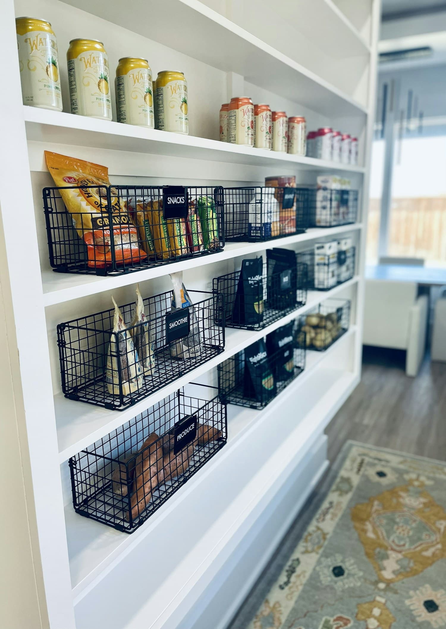 Pantry shelves lined with dark wire baskets holding snacks and dry goods.